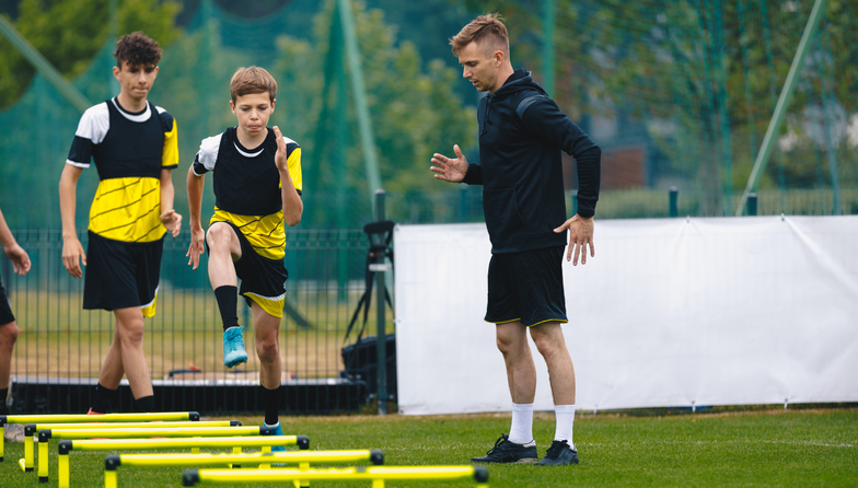 Ladder Drills for Soccer. Group of Young Boys on Football Training With Coach. Young Man as a Sports Trainer Showing to Male Youth Soccer Team how to Exercise on Agility Ladder